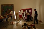 Viva La Revolucion Dzine and his diligent crew finish up his flamboyant rickshaw-esque vehicle. A work by Ryan McGinness hangs in the background.